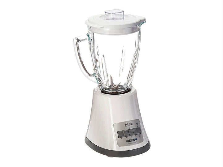 Licuadora Oster blanca con vaso de vidrio transparente y base con controles de velocidad.