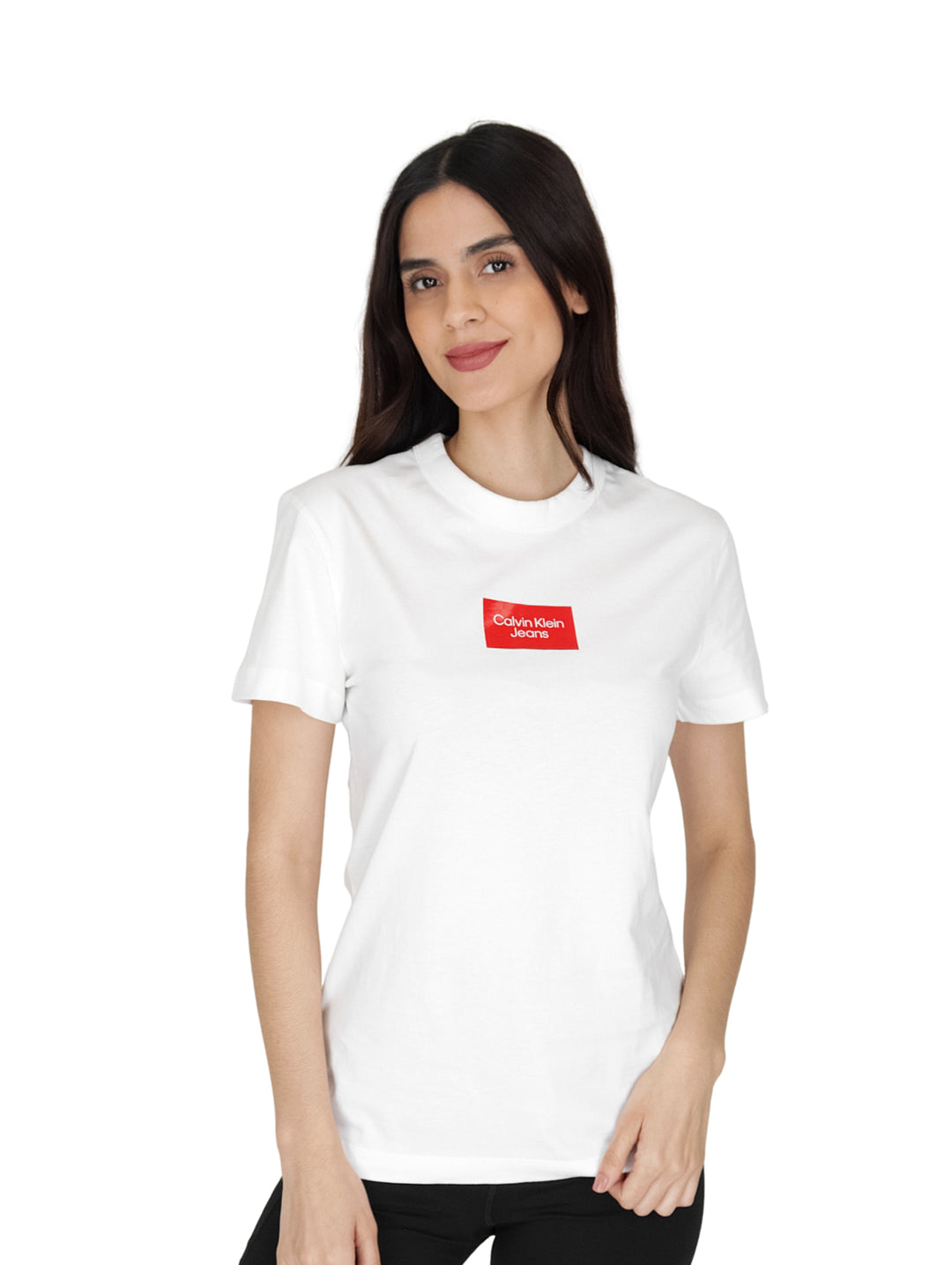 Mujer vistiendo una playera blanca de manga corta y cuello redondo con un logo rectangular rojo en el pecho.