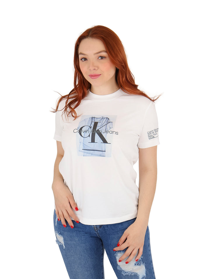 Mujer vistiendo playera blanca de manga corta con estampado central de Calvin Klein Jeans y jeans azules.