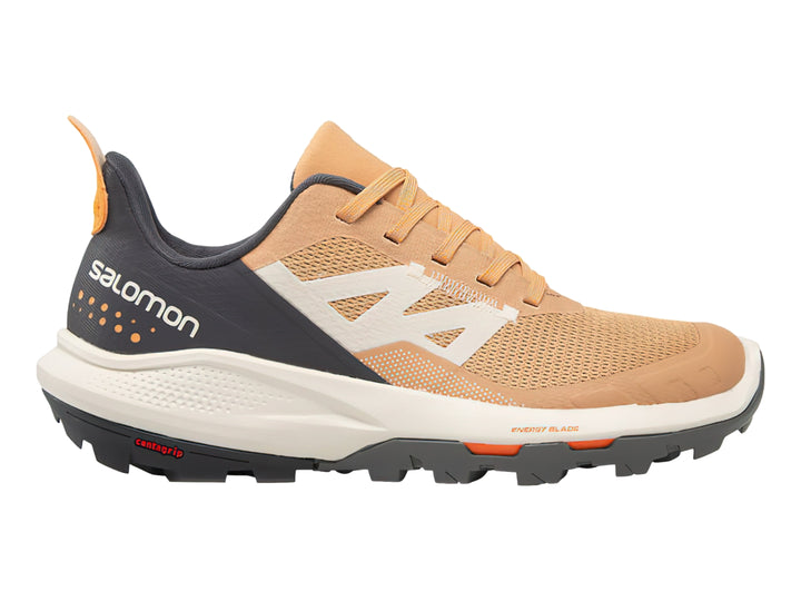 Tenis deportivos Salomon Outpulse en colores beige, gris oscuro y detalles naranjas con suela blanca y negra.