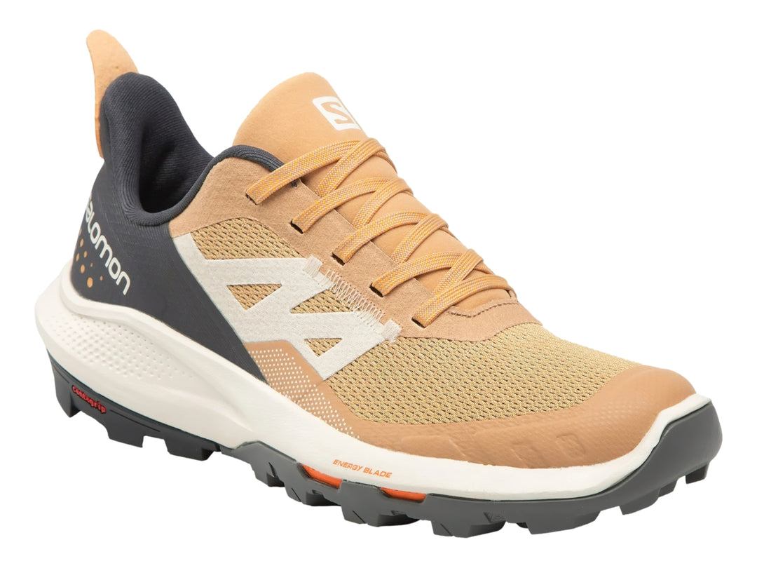 Tenis deportivos Salomon Outpulse en colores beige, gris oscuro y detalles naranjas con suela blanca y negra.
