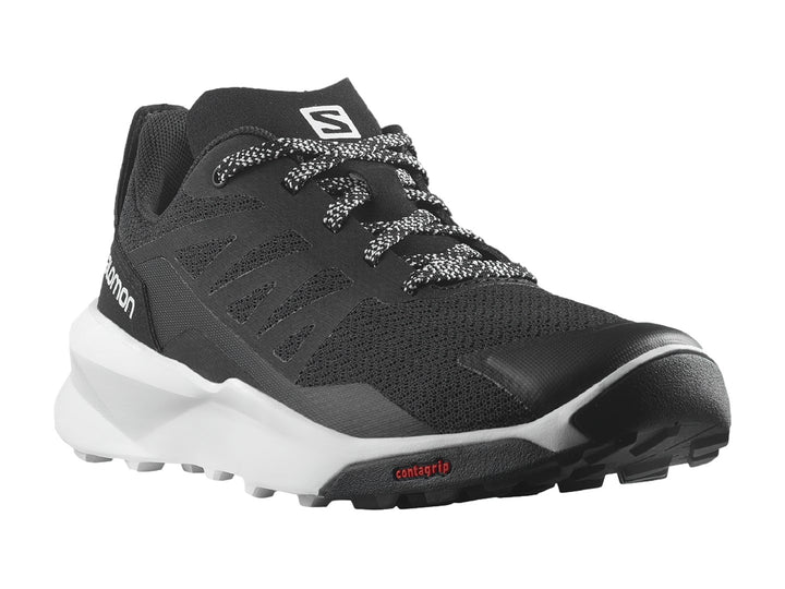 Zapato deportivo Salomon Patrol color negro con suela blanca y detalles en rojo.