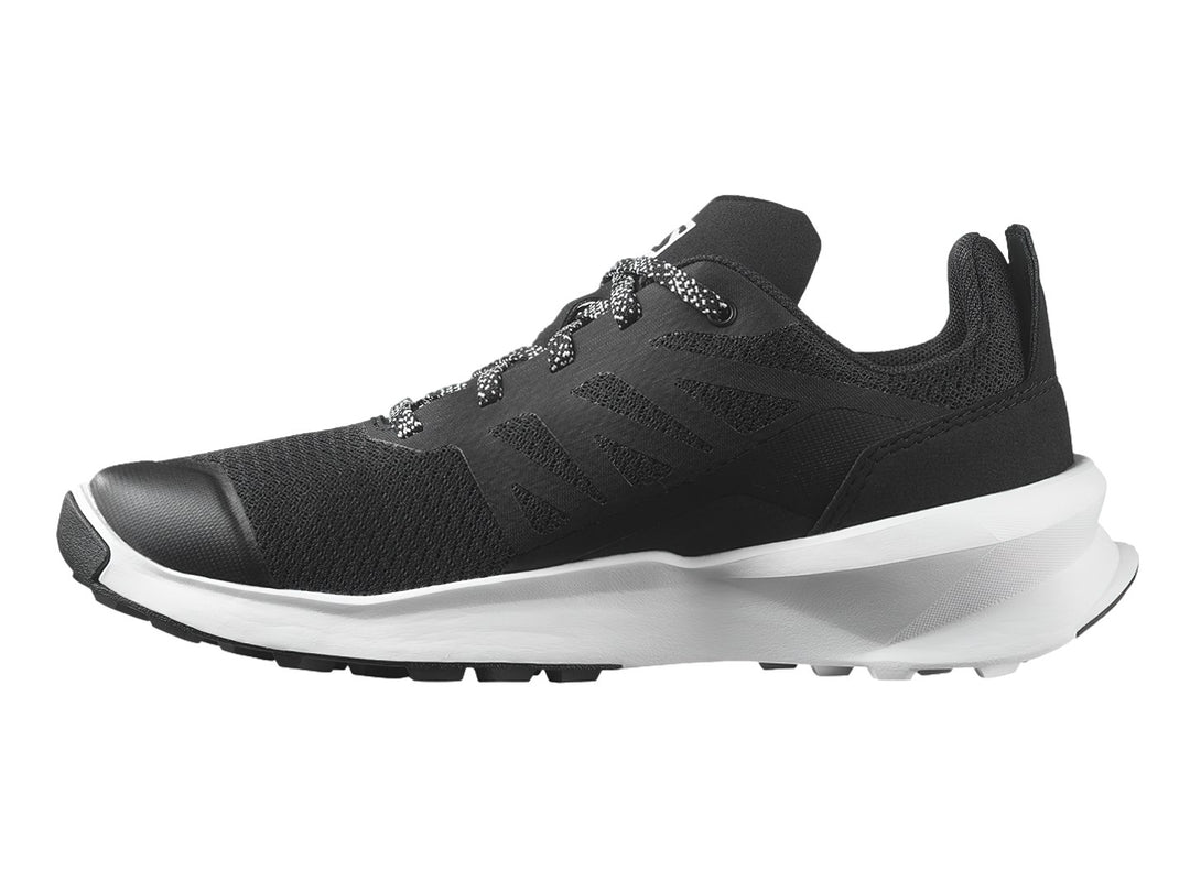 Zapato deportivo Salomon Patrol color negro con suela blanca y detalles en rojo.