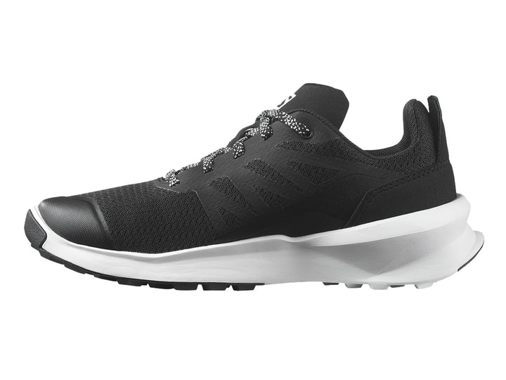 Zapato deportivo Salomon Patrol color negro con suela blanca y detalles en rojo.