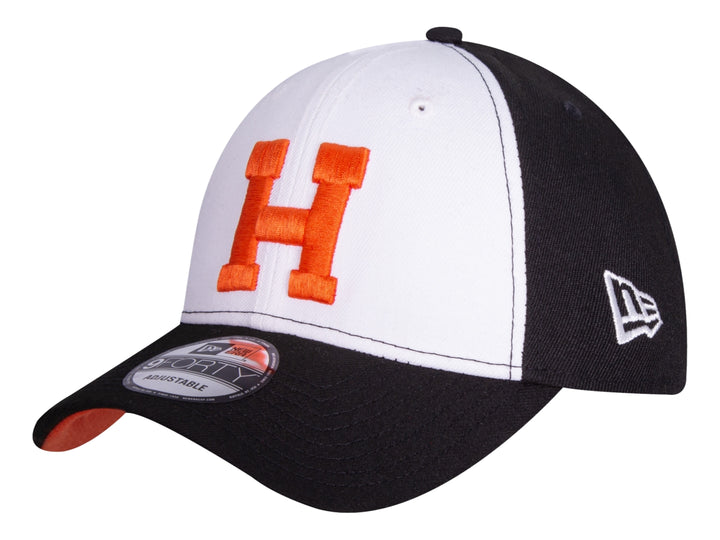 Gorra New Era bicolor en blanco y negro con letra H bordada en color naranja al frente.