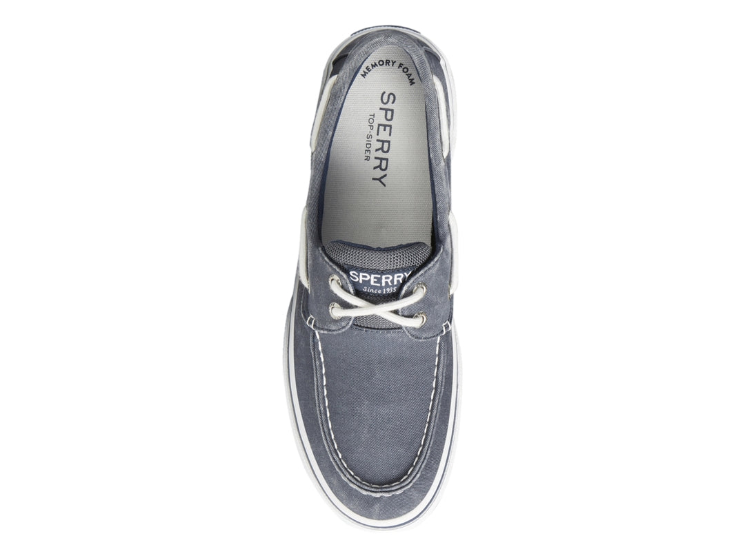Zapato náutico Sperry de tela azul marino con suela blanca y cordones blancos.