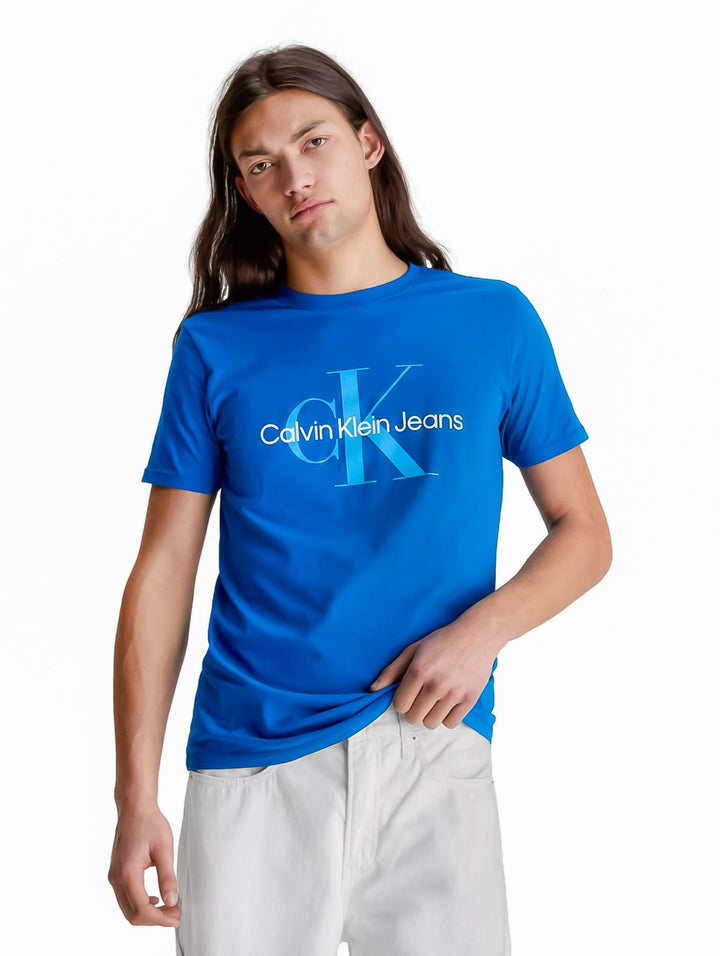 Hombre vistiendo una camiseta azul de manga corta con el logotipo de Calvin Klein Jeans en el pecho.