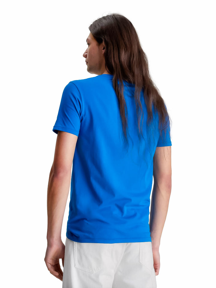 Hombre vistiendo una camiseta azul de manga corta con el logotipo de Calvin Klein Jeans en el pecho.