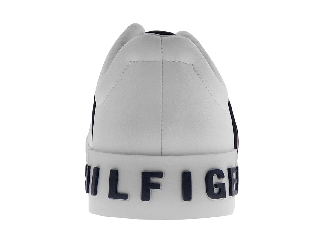 Tenis Tommy Hilfiger color blanco con franjas laterales en azul y rojo y suela blanca.