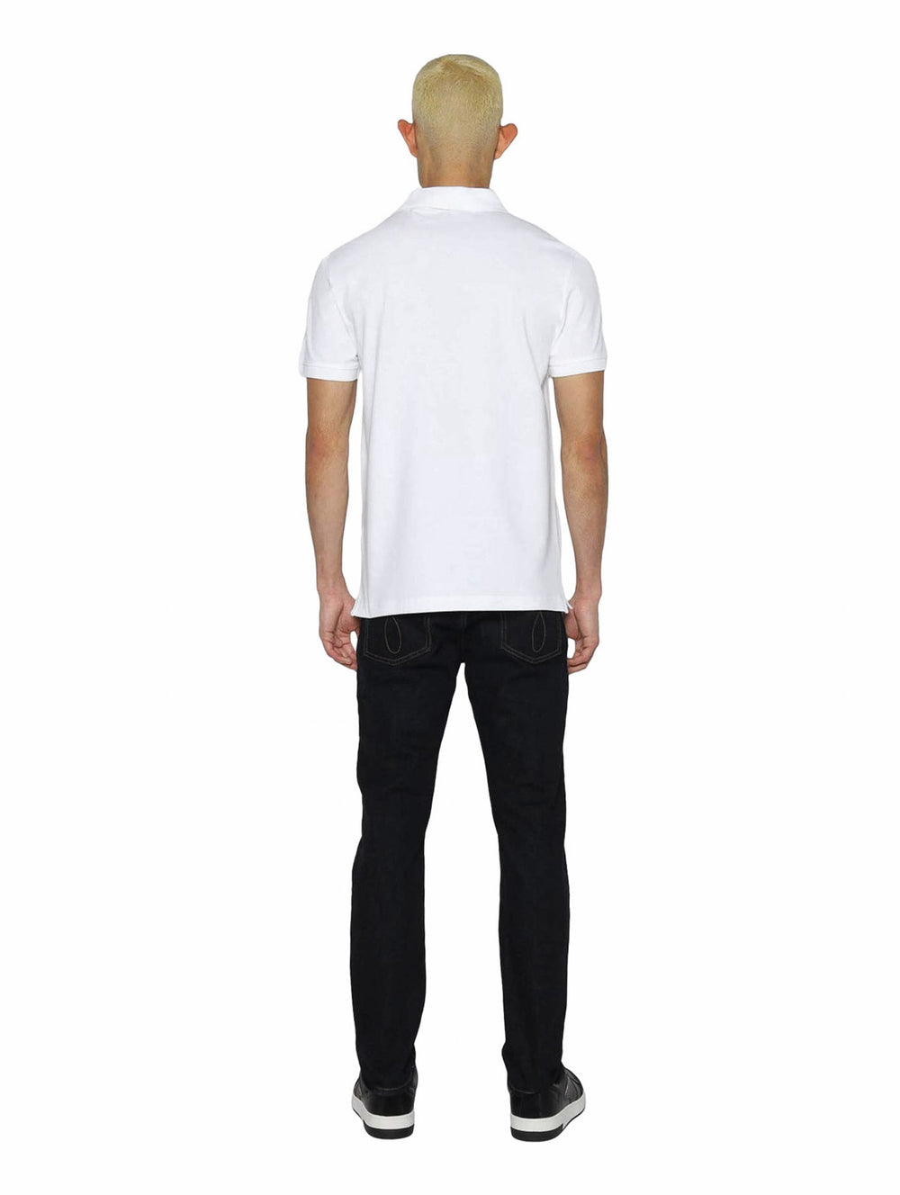 Hombre vistiendo polo blanco de Calvin Klein con cinta negra con logo en el pecho.