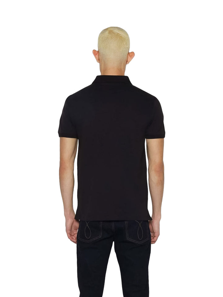 Hombre vistiendo una playera polo negra de Calvin Klein con una cinta blanca con logo en el pecho.