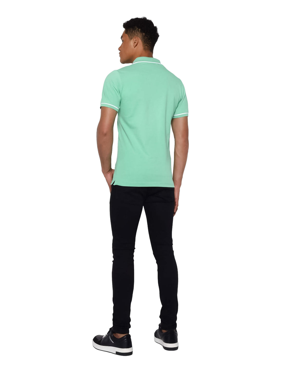Hombre vistiendo una playera polo Calvin Klein de color verde con detalles blancos en cuello y mangas.