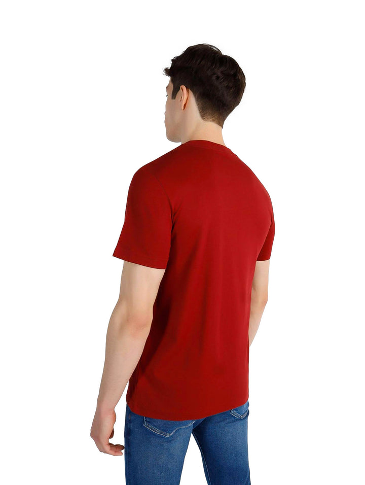 Hombre con camiseta marrón de manga corta Calvin Klein y pantalones vaqueros azules.
