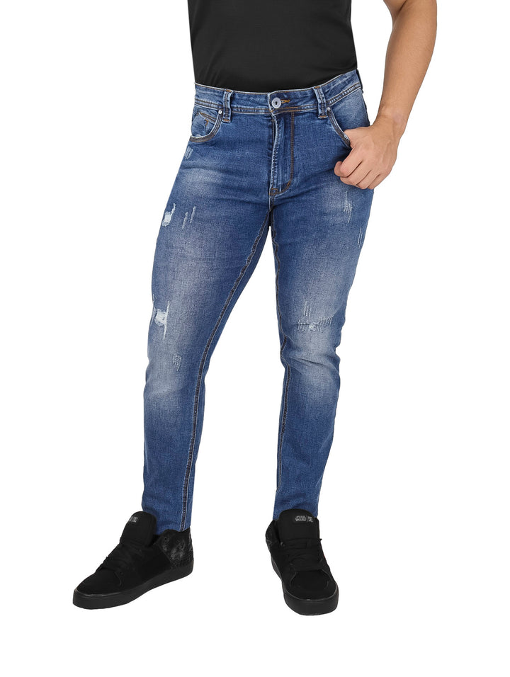Hombre usando pantalones jeans color azul con efecto de desgaste y destrucción.