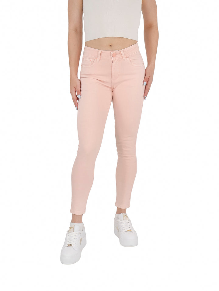 Mujer vistiendo pantalones ajustados de gabardina color rosa claro y tenis blancos.