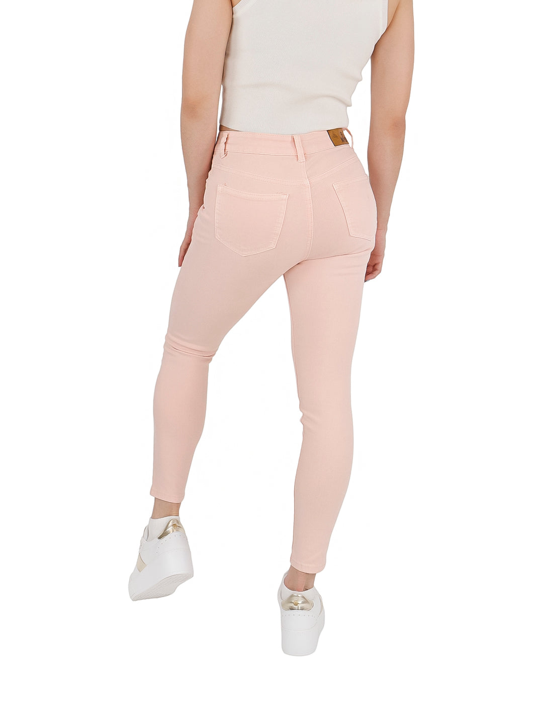 Mujer vistiendo pantalones ajustados de gabardina color rosa claro y tenis blancos.