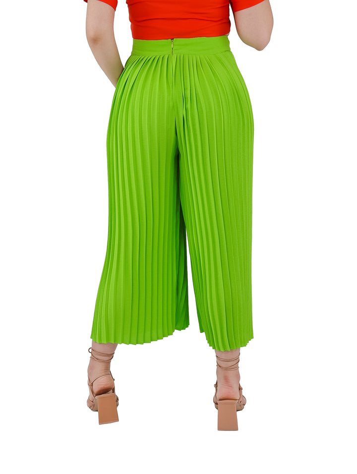 Mujer vistiendo pantalón plisado de color lima con corte ancho y cintura alta.