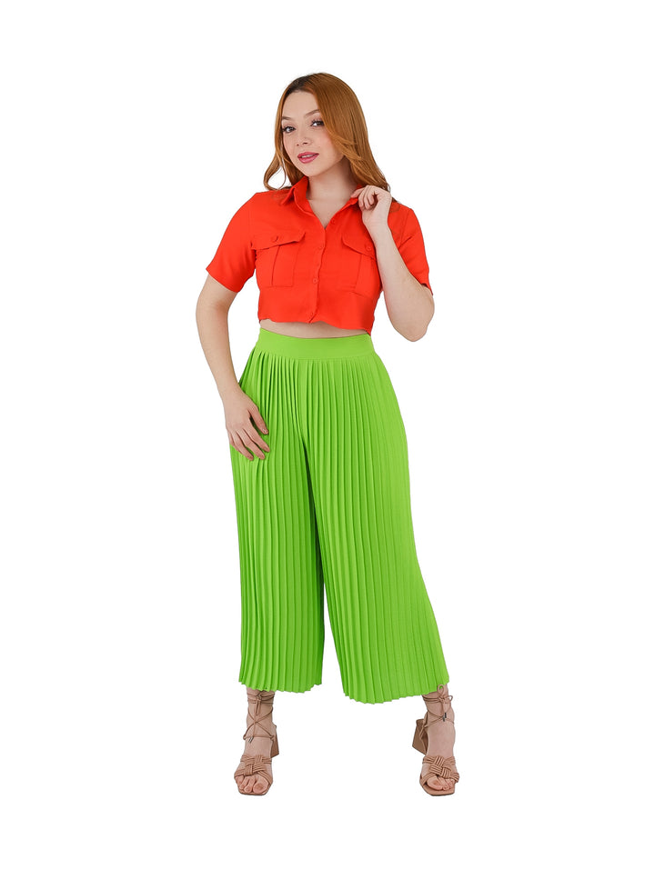 Mujer vistiendo pantalón plisado de color lima con corte ancho y cintura alta.