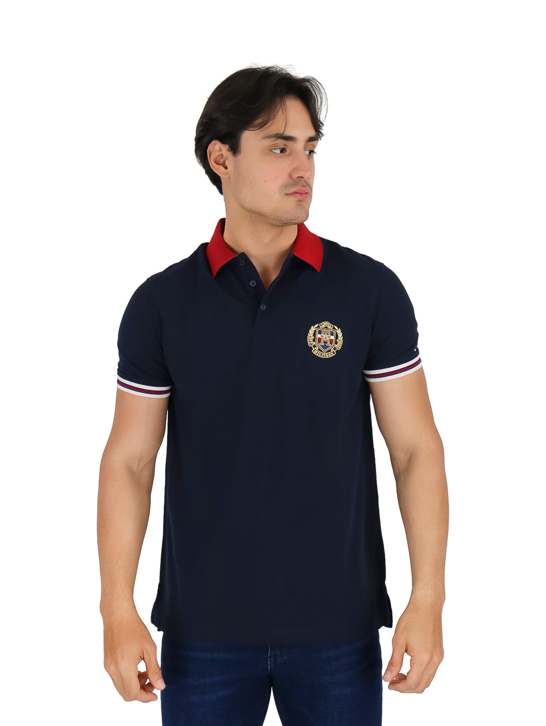 Hombre vistiendo polo Tommy Hilfiger color azul marino con cuello rojo y detalles de rayas blancas y rojas en las mangas.