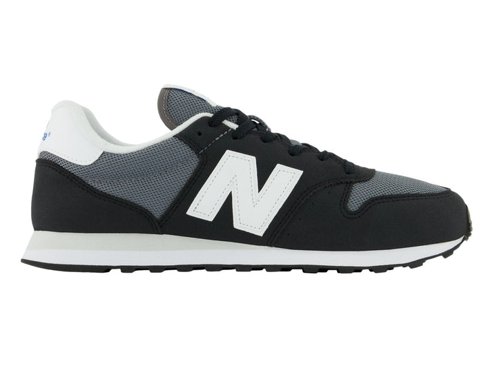Tenis New Balance color negro con suela blanca y detalles en gris, vista lateral.
