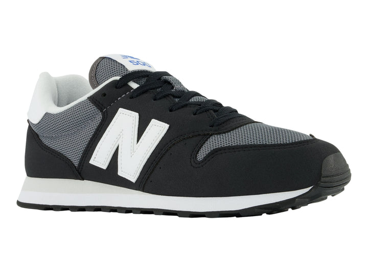 Tenis New Balance color negro con suela blanca y detalles en gris, vista lateral.
