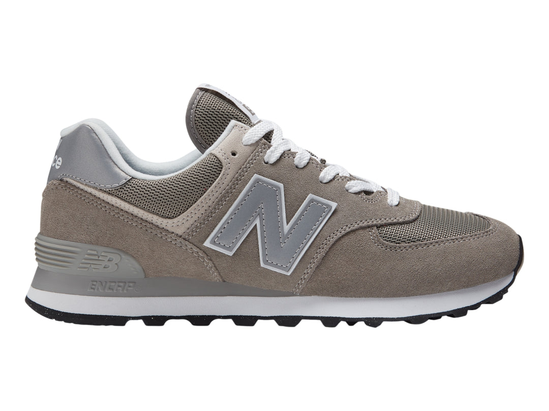 Tenis New Balance 574 color gris con suela blanca y detalles en malla.