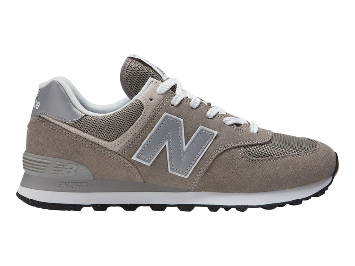 Tenis New Balance 574 color gris con suela blanca y detalles en malla.