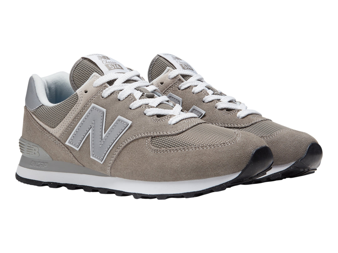 Tenis New Balance 574 color gris con suela blanca y detalles en malla.