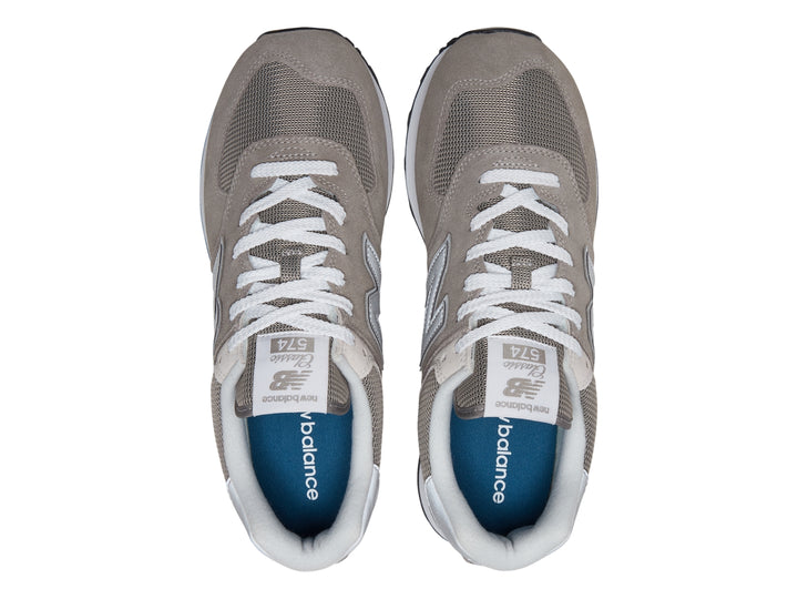Tenis New Balance 574 color gris con suela blanca y detalles en malla.