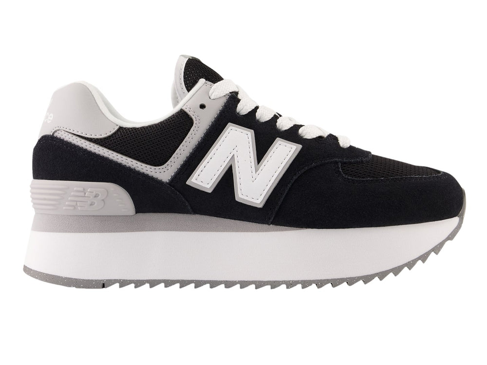 Tenis New Balance negros con suela de plataforma blanca y detalles en gris.