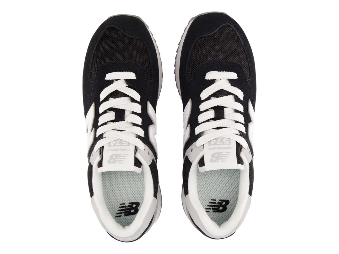 Tenis New Balance negros con suela de plataforma blanca y detalles en gris.