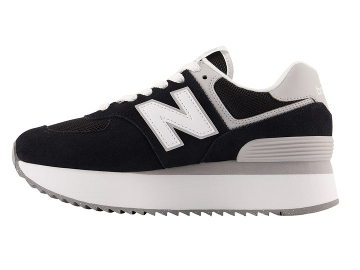 Tenis New Balance negros con suela de plataforma blanca y detalles en gris.