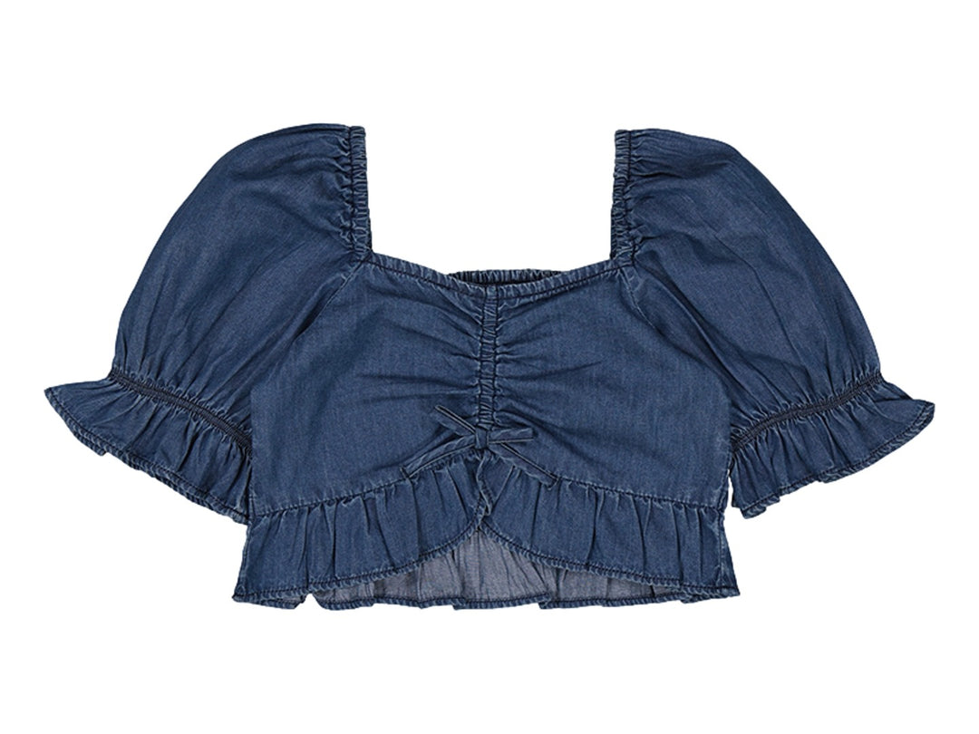 Blusón azul tipo denim con mangas abullonadas, fruncido central y volante inferior.