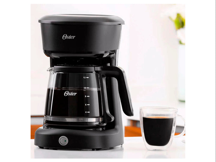 Cafetera Oster color negro con jarra de vidrio graduada para 12 tazas sobre fondo blanco.