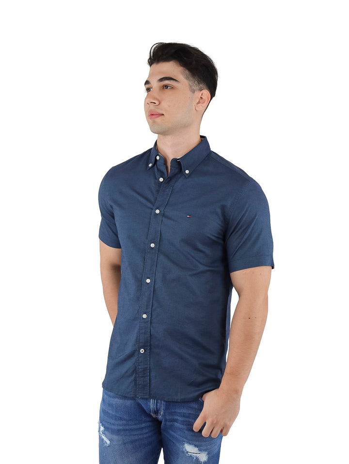 Hombre vistiendo una camisa Tommy Hilfiger de manga corta en color azul marino y jeans azules.