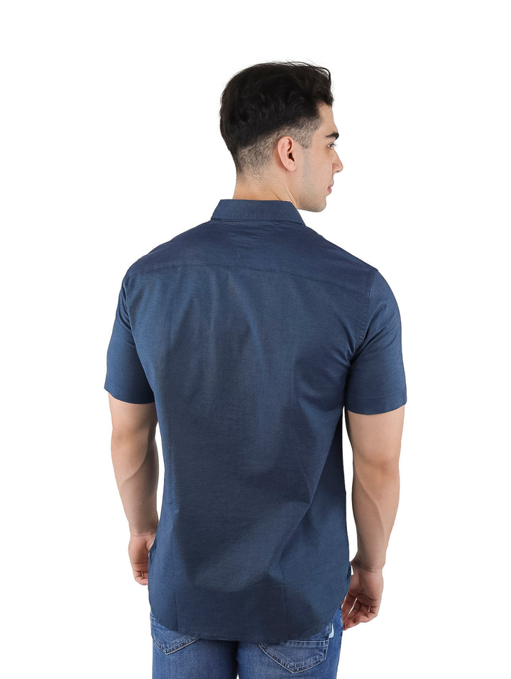 Hombre vistiendo una camisa Tommy Hilfiger de manga corta en color azul marino y jeans azules.