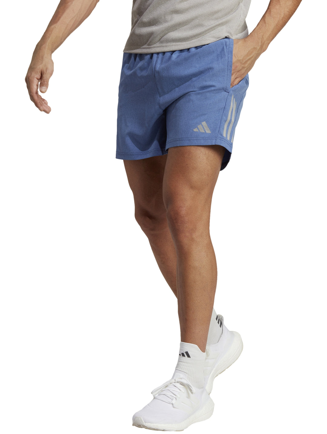Hombre vistiendo shorts deportivos Adidas de color azul con tenis blancos.