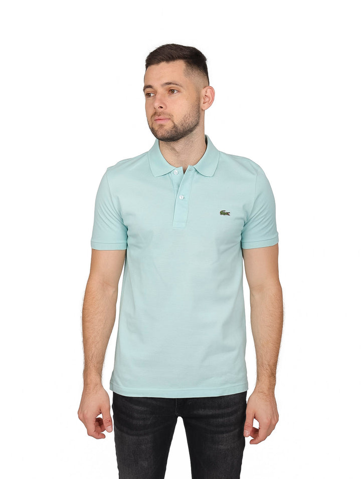 Hombre vistiendo una camiseta polo Lacoste de color verde pastel con cuello acanalado y manga corta.