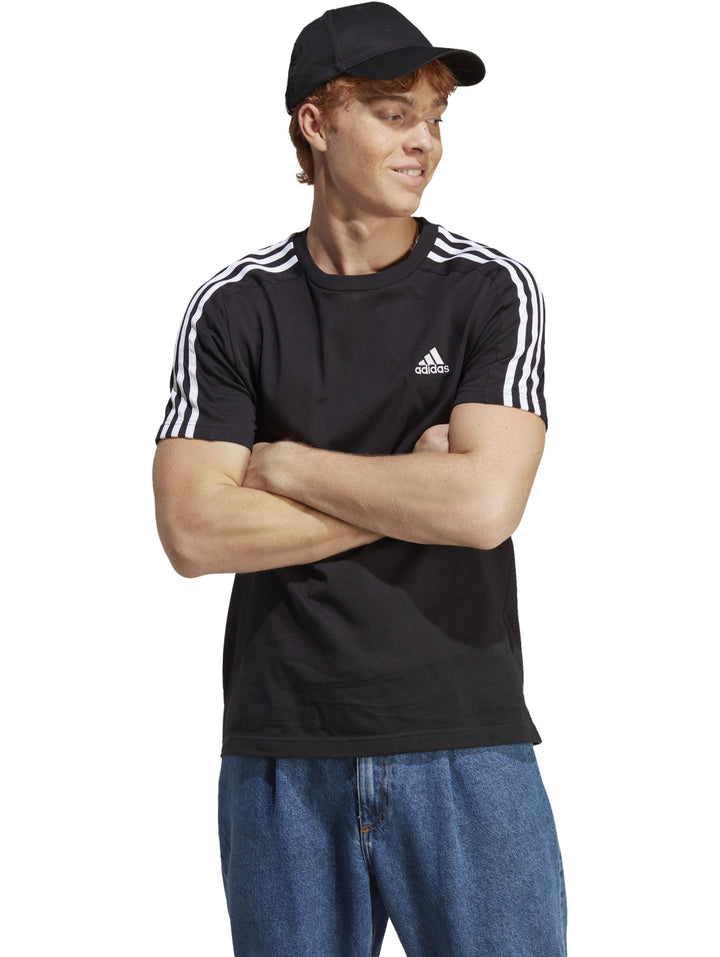 Hombre vistiendo camiseta deportiva Adidas color negro con tres rayas blancas en los hombros.