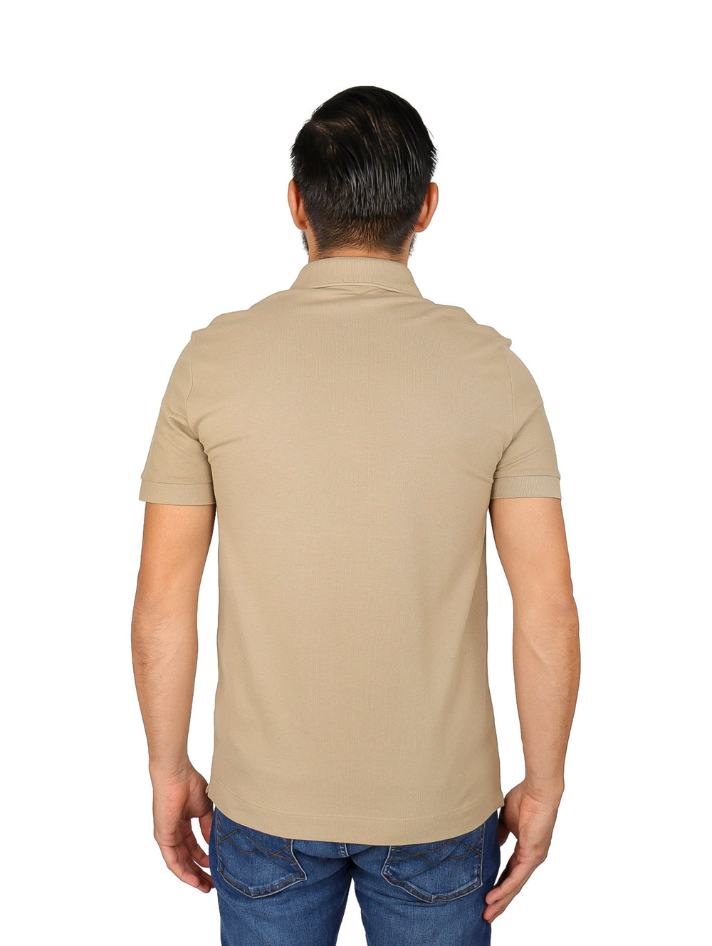 Hombre vistiendo una camiseta polo Lacoste de color beige con cuello acanalado y manga corta.
