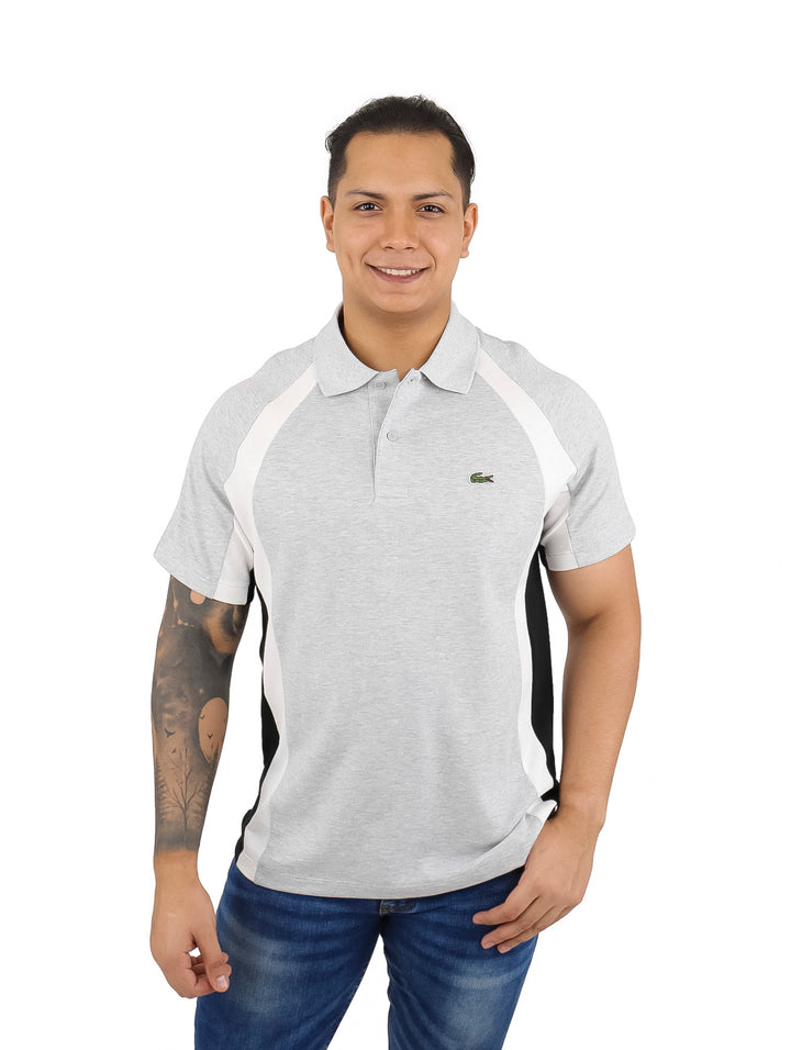 Hombre usando polo Lacoste gris claro con franjas laterales en blanco y azul marino.