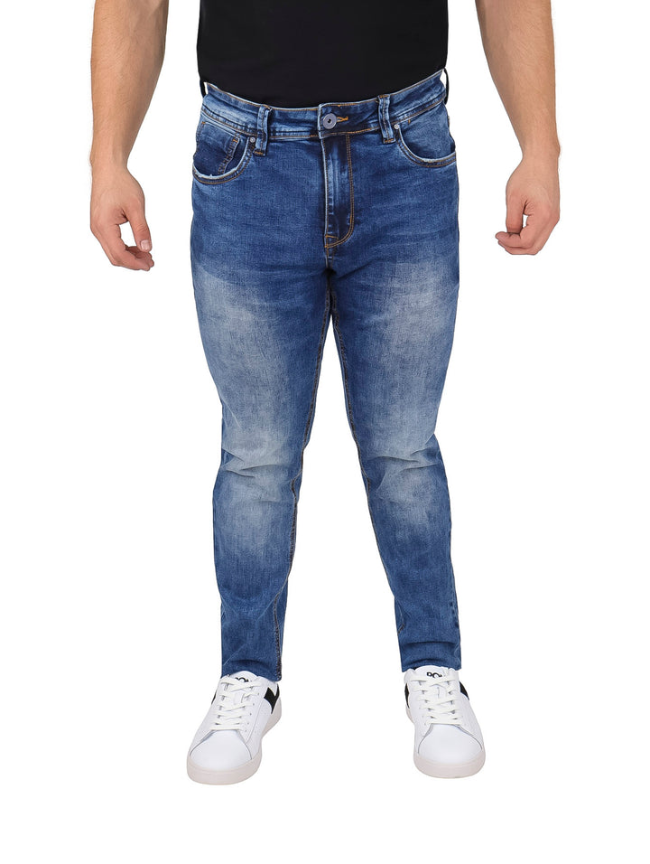 Hombre vistiendo pantalones jeans azules con efecto lavado y costuras naranjas.