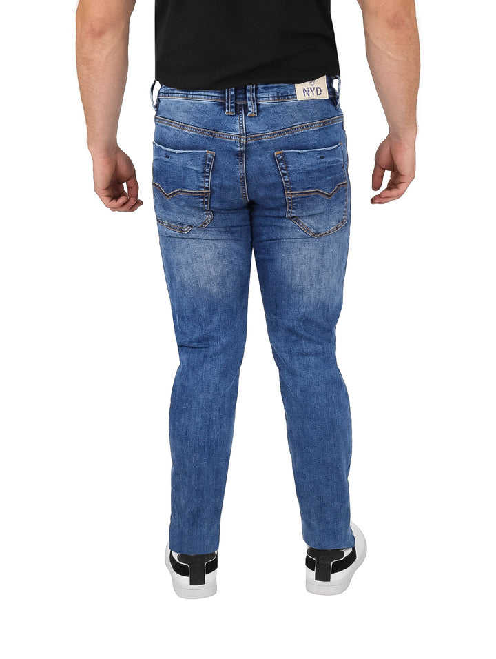Hombre vistiendo pantalones jeans azules con efecto lavado y costuras naranjas.