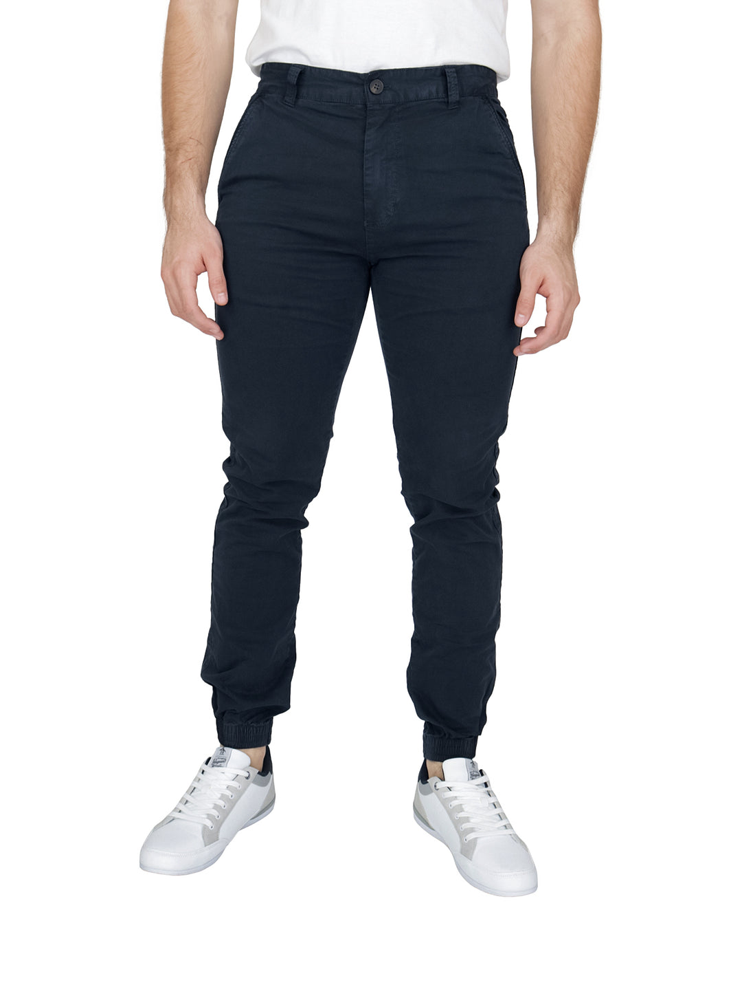 Hombre vistiendo pantalones tipo jogger color azul marino con calzado blanco sobre fondo blanco.