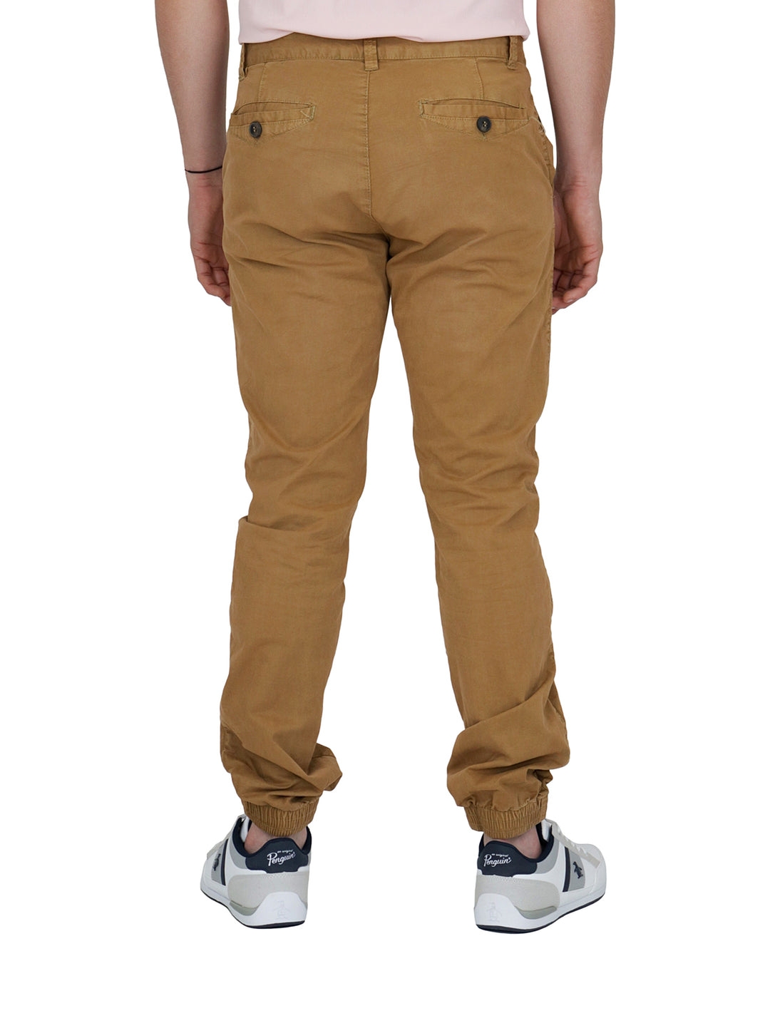 Hombre vistiendo pantalones tipo jogger color camel con calzado blanco sobre fondo blanco.