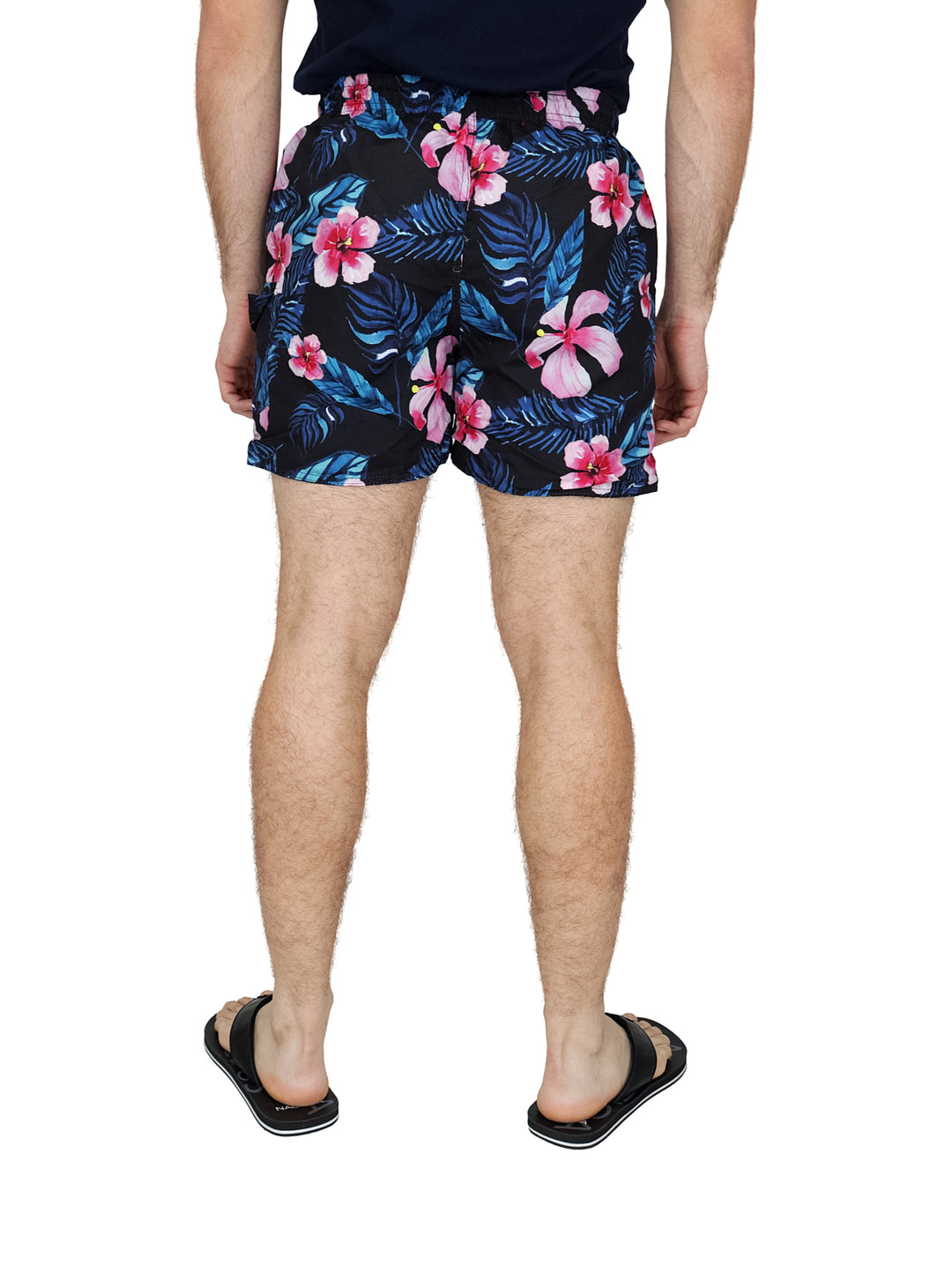 Hombre usando traje de baño corto negro con estampado de flores rosas y hojas azules.