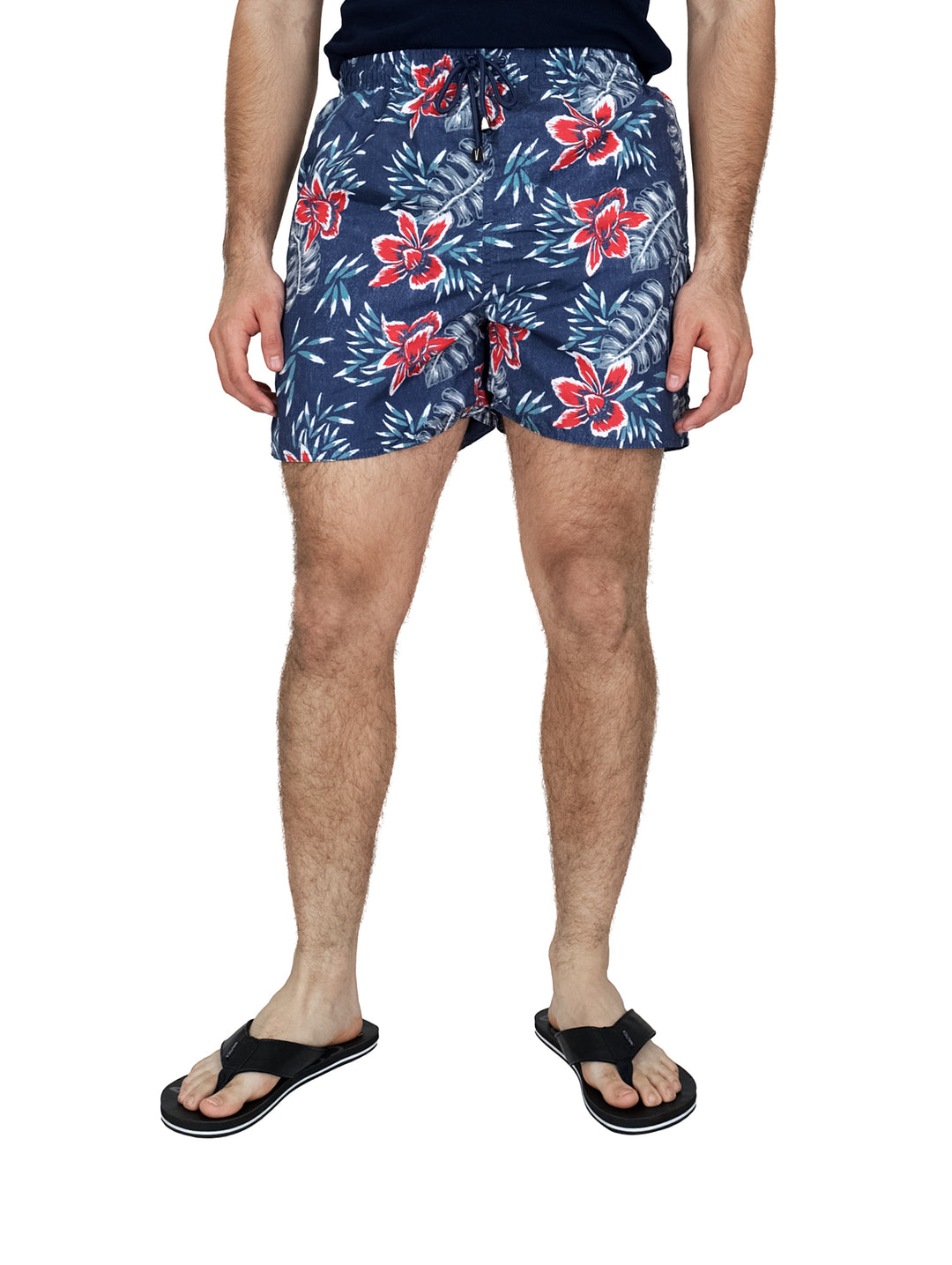 Hombre vistiendo traje de baño corto color azul marino con estampado de flores rojas y blancas.