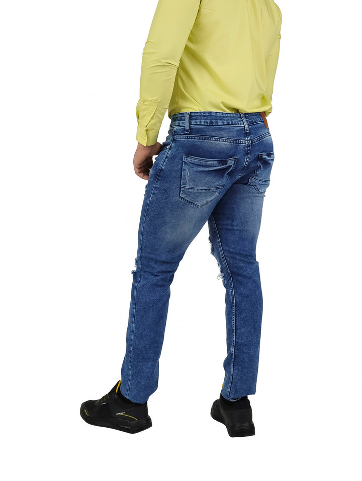 Hombre vistiendo pantalones jeans color azul con detalles de destrucción en las rodillas.