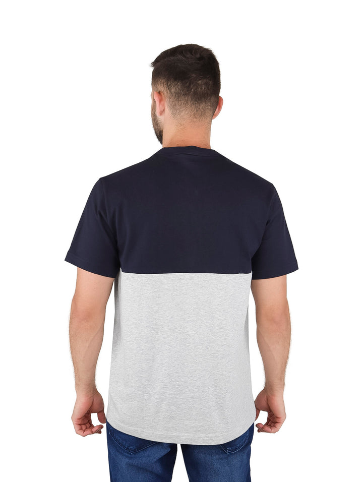 Hombre vistiendo camiseta Lacoste de dos tonos en azul marino y gris con logotipo frontal.