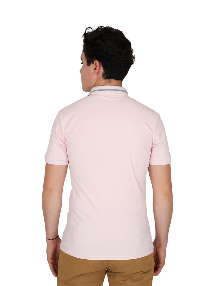 Hombre vistiendo una playera tipo polo de color rosa claro con cuello detallado y pantalones color caqui.